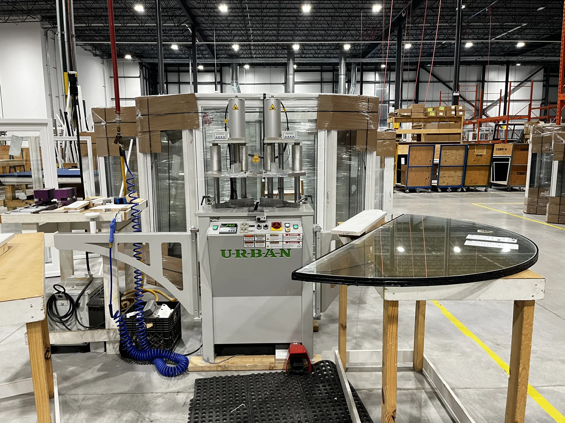 Window production machinery beside a shaped glass unit